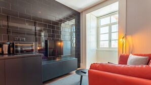 A modern kitchen with dark tiles, a built-in microwave, and a red leather sofa. - FLH Viola Market Flat I (Funchal)