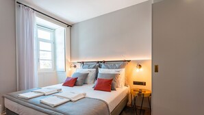 A modern hotel room with a neatly made bed, a bedside table, and a window with curtains. - FLH Viola Market Flat I (Funchal)