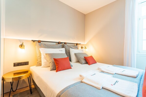 Ein Hotelzimmer mit Bett, Kissen, Nachttisch und Fenster.