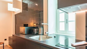 A modern kitchen with a stainless steel sink, a toaster, and a coffee maker on the countertop. - FLH Viola Market Flat IV (Funchal)