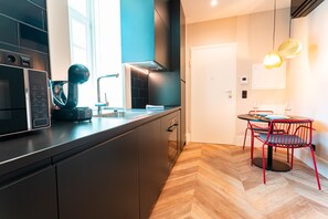 Cuisine moderne équipée d’un four à micro-ondes, d’une bouilloire et d’une machine à café. Un coin repas avec une table et des chaises est également à disposition.
