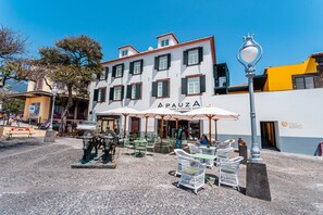 Un bâtiment avec une enseigne indiquant « APAUZA » et des tables à l’extérieur, protégées par des parasols.