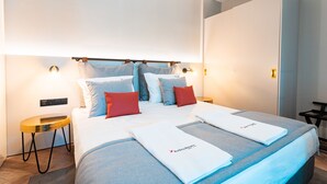 Una habitación de hotel moderna con una cama bien hecha, una mesita de noche y una lámpara.