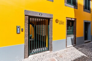 Un bâtiment à la façade jaune, avec un panneau portant le chiffre «  3 » au-dessus d’une porte et une enseigne « VIVA MARKET » sur le mur.