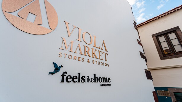 Un edificio con un letrero que indica 'Viola Market Stores & Studios' y 'feels like home Holiday Rentals'.