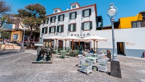 A building with a sign reading "APAUZA" and outdoor seating with umbrellas. - FLH Viola Market Flat V (Funchal)