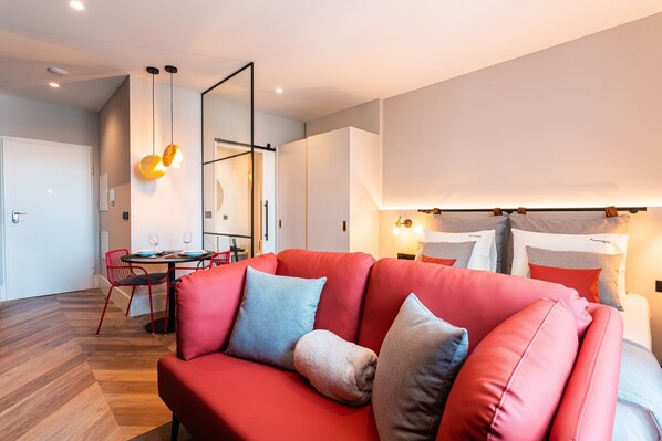 Un salon moderne avec un canapé rouge, une table à manger avec des chaises et un grand miroir.