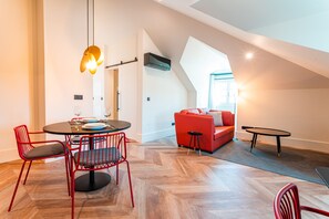 A modern living space with a dining area, red chairs, a red sofa, and a small table. - FLH Viola Market with Terrace I (Funchal)