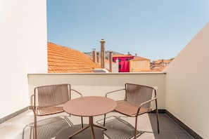 A balcony with two wicker chairs and a small round table, overlooking a cityscape with red-roofed buildings. - FLH Viola Market with Terrace I (Funchal)