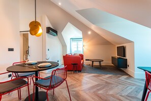 A modern living space with a dining area, a red sofa, and a TV mounted on the wall.