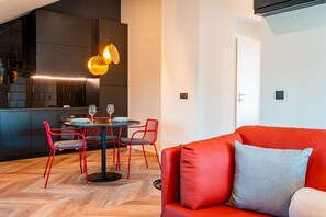 Un espace de vie moderne comprenant un canapé rouge, une table à manger avec des chaises et un coin cuisine.