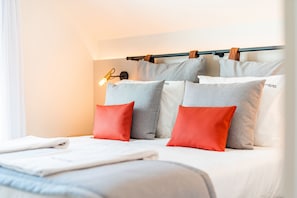A neatly made bed with white and grey bedding, a headboard with a light fixture, and a window with white curtains. - FLH Viola Market with Terrace I (Funchal)