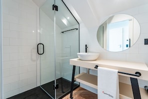 A modern bathroom with a glass shower enclosure, a white sink, and a round mirror. - FLH Viola Market with Terrace I (Funchal)