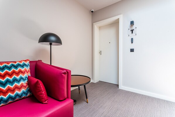 A modern room with a red sofa, a small round table, a black floor lamp, and a white door.