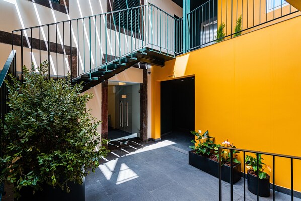 A multi-level interior with a staircase, potted plants, and a yellow wall. - FLH Viola Market with Terrace II (Funchal)