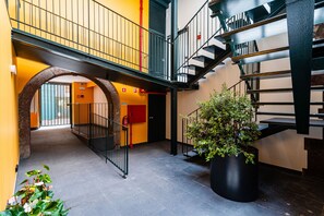 Un intérieur à plusieurs niveaux, avec un escalier, une grande plante en pot et un mur jaune.