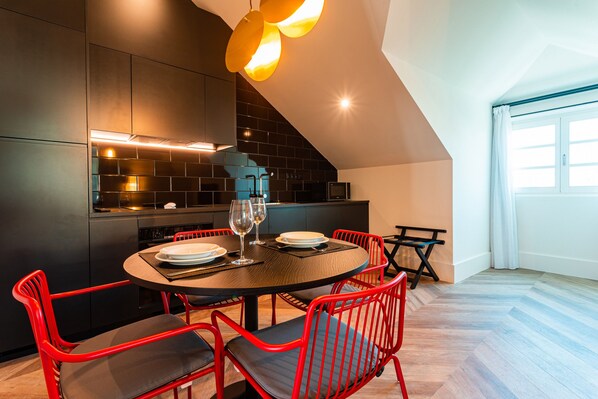 Une cuisine moderne avec des meubles de couleur sombre, une table de salle à manger ronde, des chaises rouges et un îlot central bien visible.