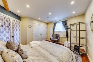 A bedroom with a bed, a chair, a wardrobe, a radiator, and a shelf unit.