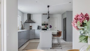 A modern kitchen with grey cabinets, a central island, and a stainless steel range hood.