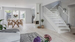 A spacious living area with a wooden dining table, a staircase, and a cozy seating area.