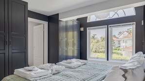 A bedroom with a large bed, a skylight, and a view of a house.