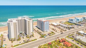 Un hôtel situé sur la côte, avec plusieurs étages, un parking et une vue sur la plage.