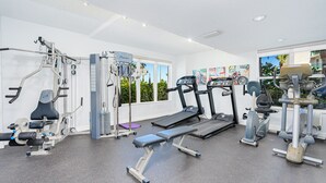 Une salle de sport équipée de machines de cardio, de matériel de musculation et d’un banc.