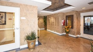 Un hall d’entrée comprenant un comptoir de réception, une plante, un distributeur de cartes-clés fixé au mur et une porte.
