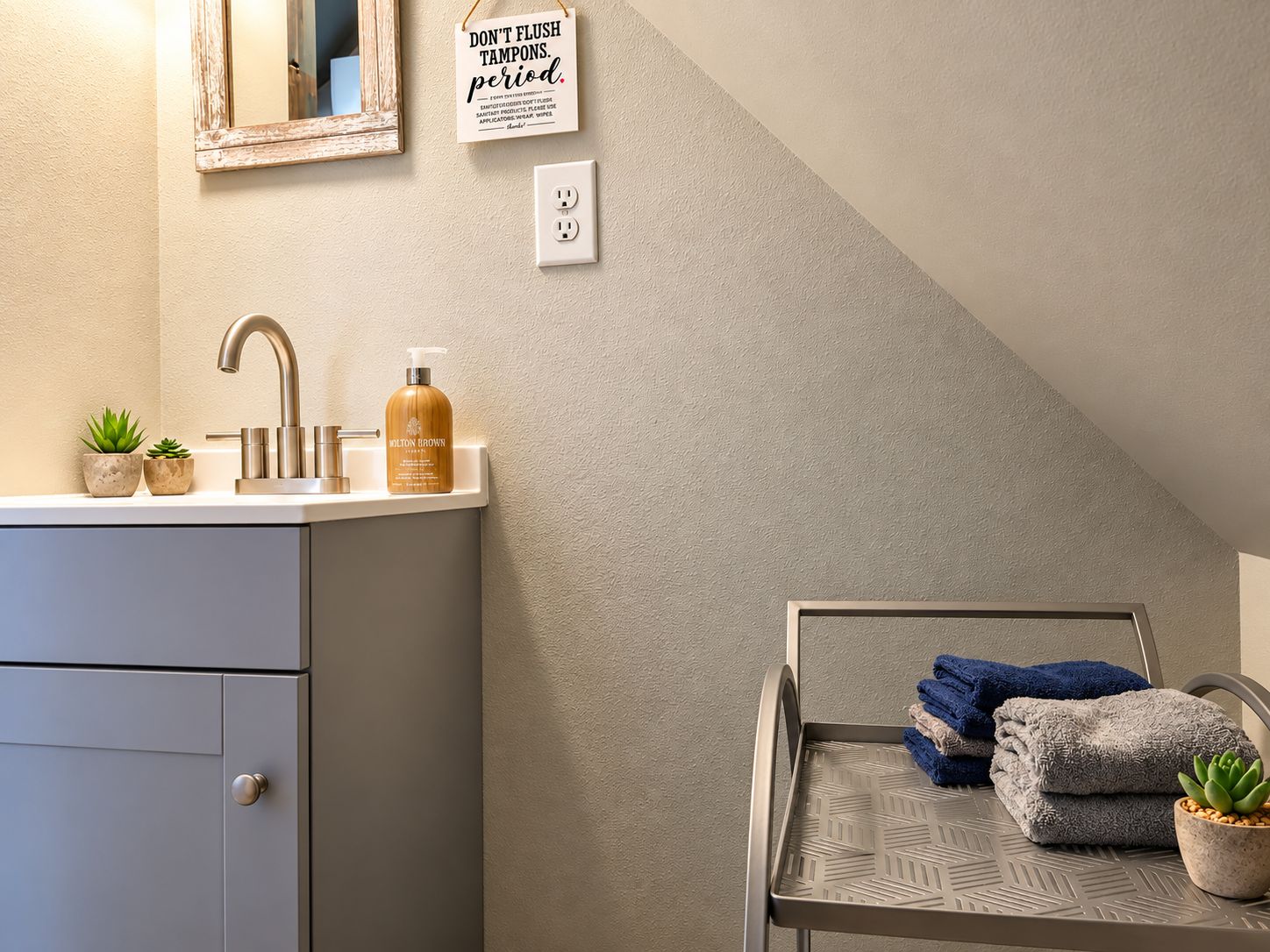 A bathroom with a sink, a mirror, a towel rack, and a wall-mounted sign.