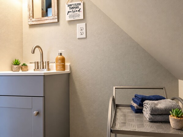 Une salle de bain équipée d’un lavabo, d’un miroir, d’un porte-serviettes et d’un panneau fixé au mur.