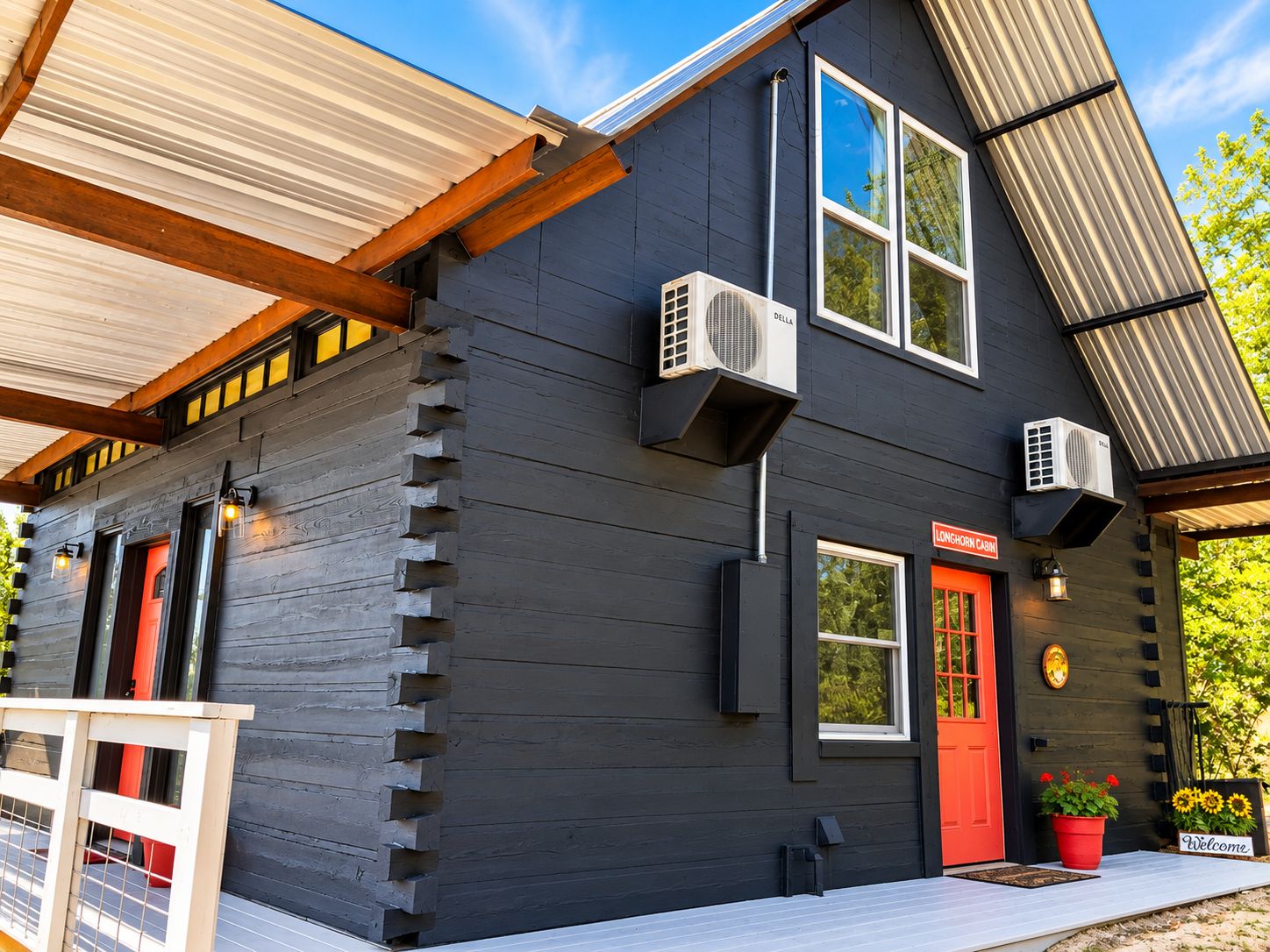 A log cabin with a red door, air conditioning units, and a welcome sign.