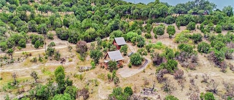 A remote, natural landscape with two cabins surrounded by dense greenery.