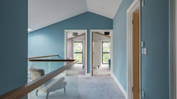 A modern interior with a glass staircase, a view of a bedroom, and a hallway leading to another room.