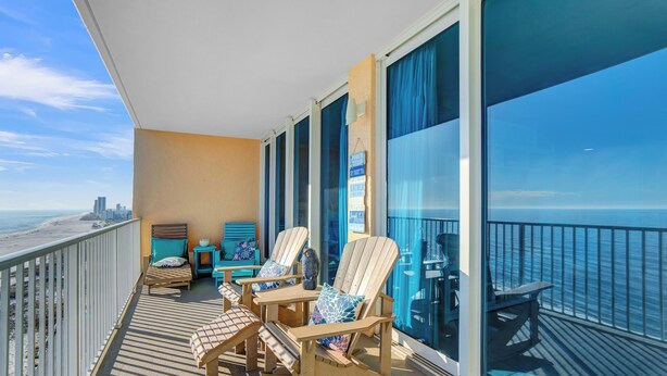A balcony with a view of the ocean and city skyline, furnished with rocking chairs and a small table. - San Carlos 1407 by Liquid Life (Gulf Shores)
