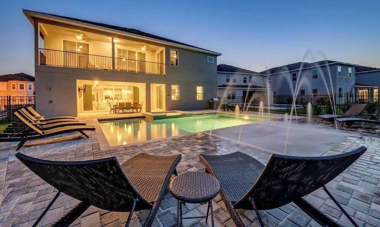 Een huis met twee verdiepingen, een zwembad, terras en een fontein.