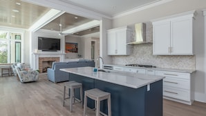 Una cocina moderna con una isla grande, muebles blancos y una chimenea.