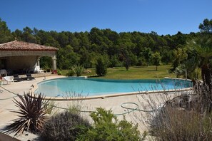 A swimming pool with a covered area and lounge chairs, surrounded by greenery and trees. - The MAJACA at FLAYOSC (Flayosc)