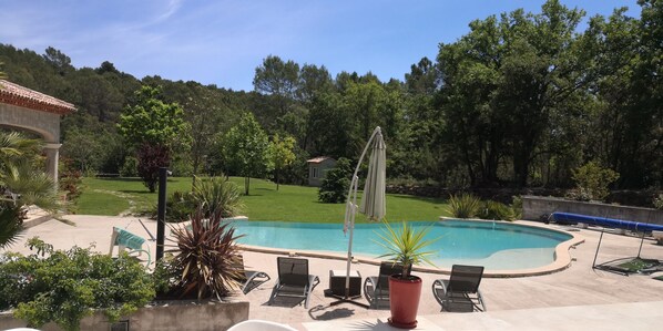 A swimming pool with lounge chairs and umbrellas, surrounded by greenery and trees. - The MAJACA at FLAYOSC (Flayosc)