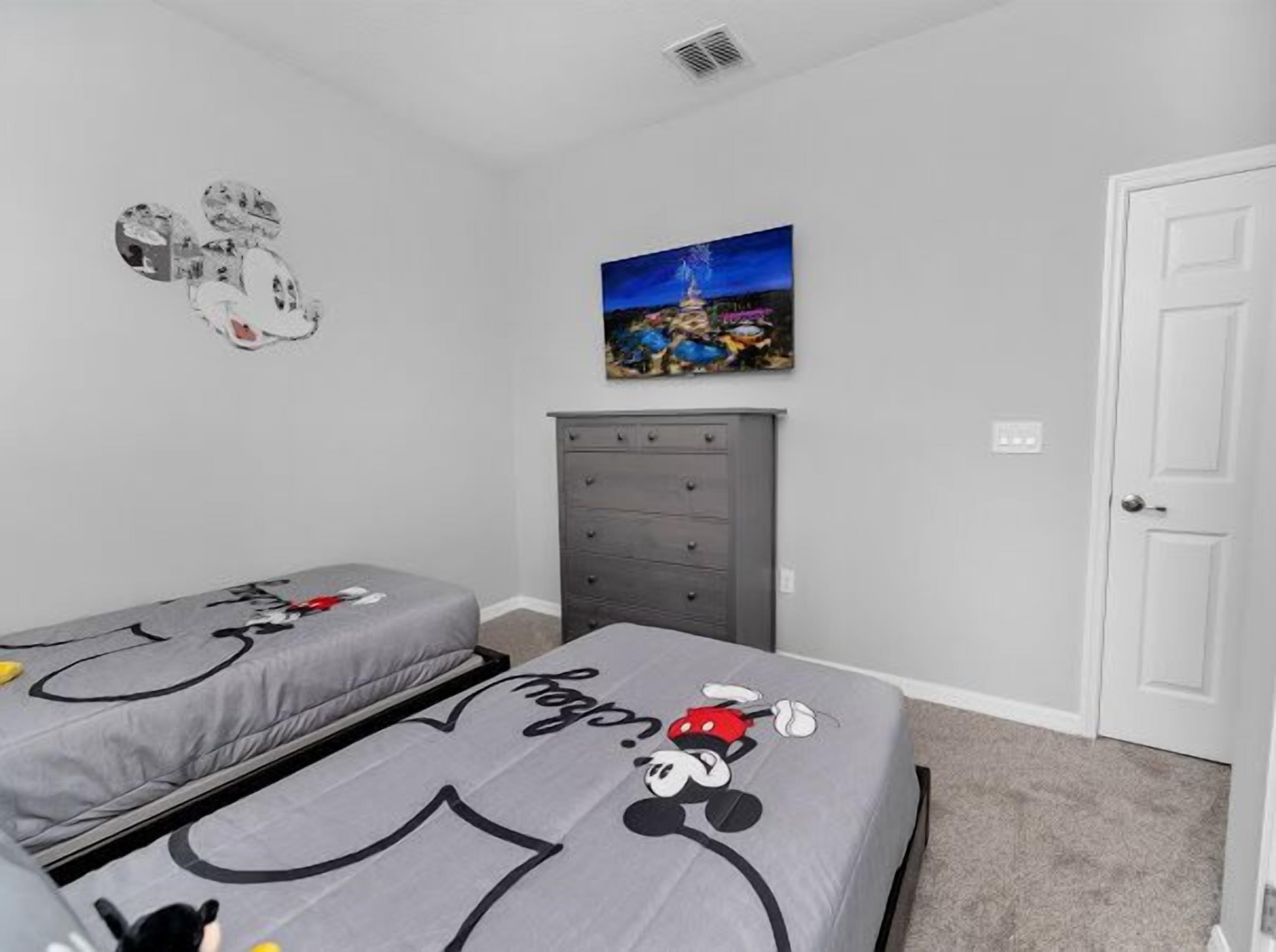 A bedroom with two beds, a dresser, a door, and a painting on the wall.