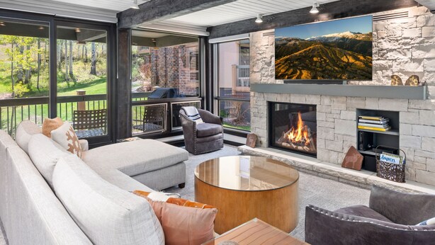 Una sala de estar moderna con chimenea, ventanas amplias y una pared de acento de piedra.