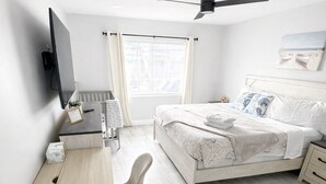 A modern bedroom with a bed, desk, chair, and a ceiling fan. - Paradise Palms Beach house with HEATED POOL🏖🌅🐬 (Largo)