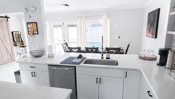 A modern kitchen with white cabinets, a large island, and a view of the city. - Paradise Palms Beach house with HEATED POOL   🏖🌅🐬 (Largo)