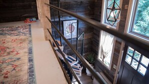 A wooden staircase with a handrail, a patterned rug, and a framed picture on the wall.