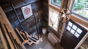 A wooden interior with a staircase, a door, and a window with curtains.