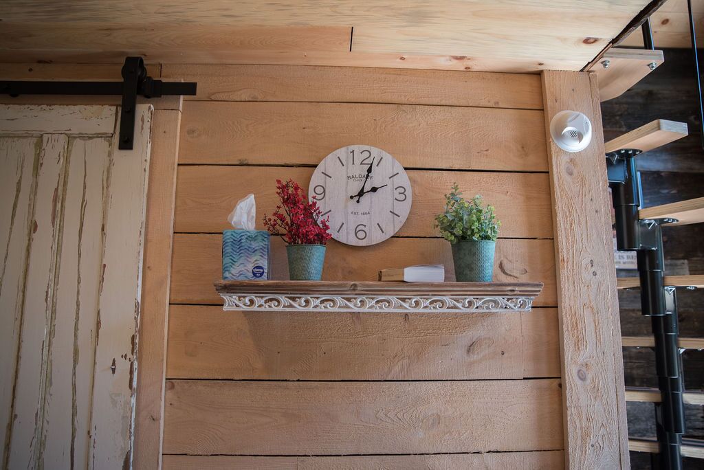 A wooden wall with a clock, a shelf with decorative items, and a door.