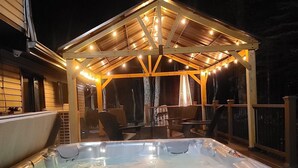 Een hottub met een houten terras en een overdekte zithoek met lichtslingers.