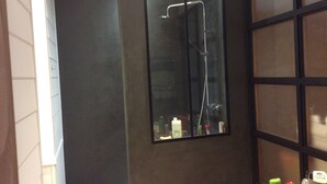 Ett modernt badrum med en dusch som är avskärmad med glasväggar, en spegel och hygienartiklar på bänkskivan.