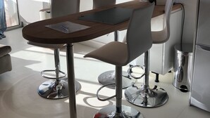 Un espace repas moderne avec une table en bois, quatre chaises et un téléviseur à écran plat fixé au mur.