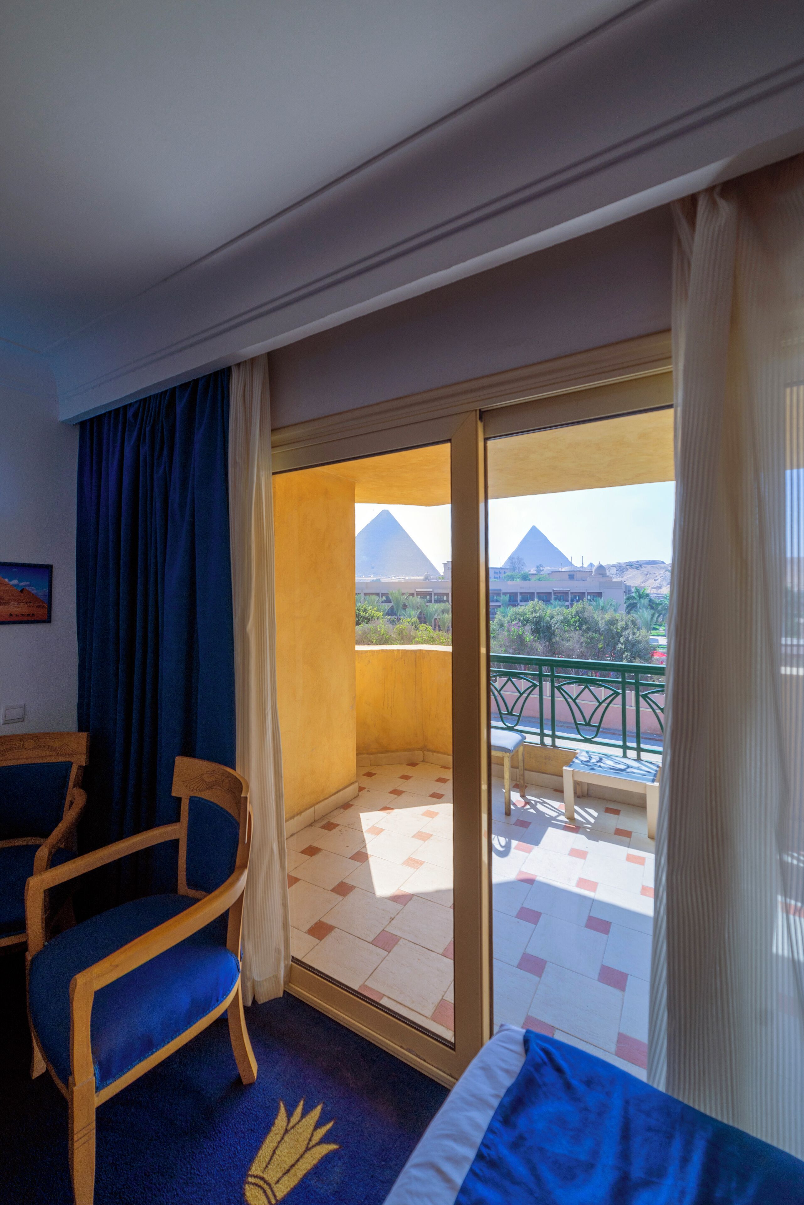 A hotel room with a balcony, a bed, a desk, and a chair.