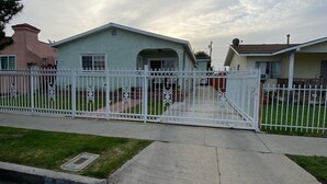 A gated residential area with a light blue house, a pink house, and a white house. - Rigo’s Apartment  (South Gate)